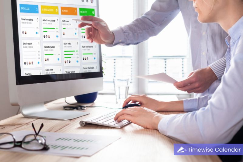 Two professionals collaborate on a computer displaying an Agile project management board using Agile methodology